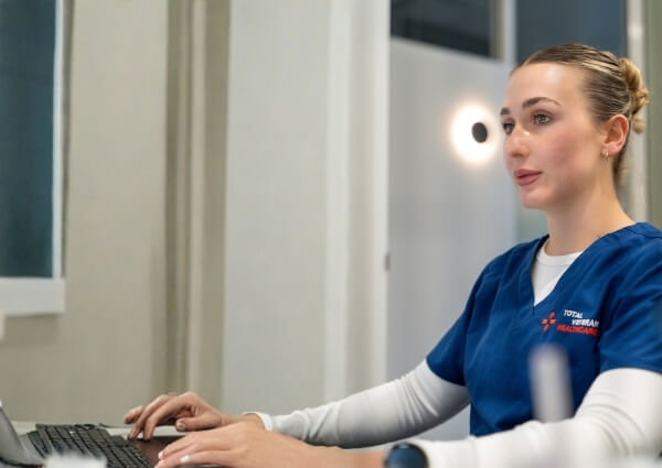 Total Veteran Healthcare clinician working on a laptop in a clinical setting